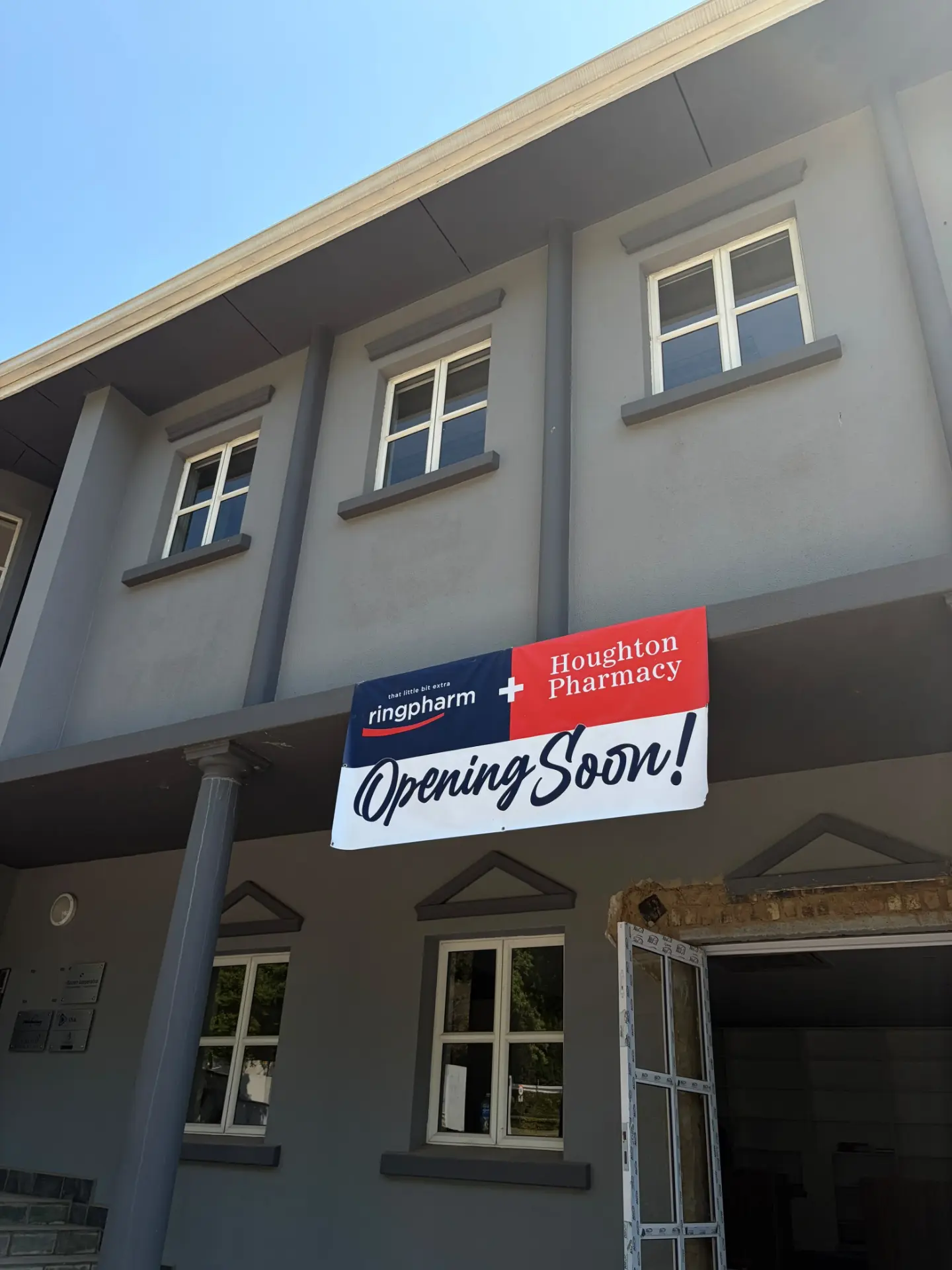 Houghton Pharmacy building with opening announcement banner.